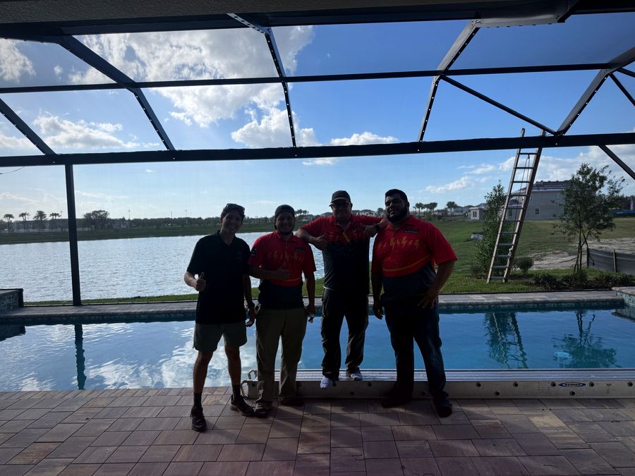 A certified install crew beside a finished pool enclosure lighting job on a lakefront home