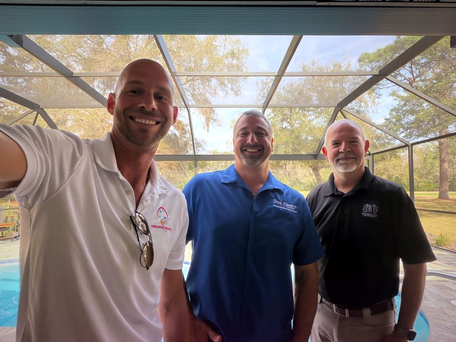 A Brighter Nights representative with a distributor and a fabricator under a finished screen enclosure