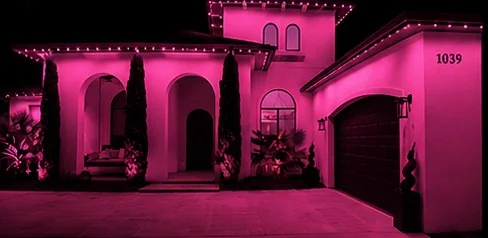 The home washed edge to edge in solid pink from the roofline fixtures