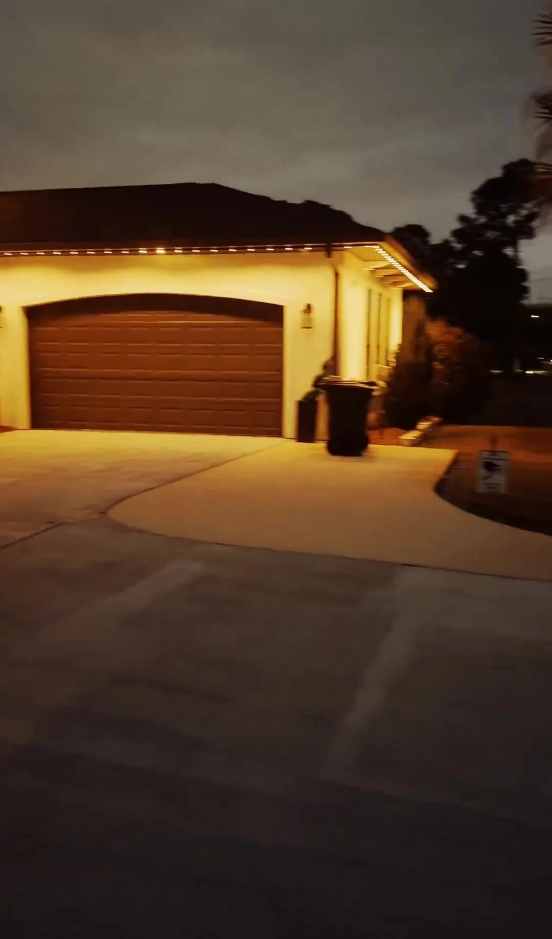 Warm white permanent roofline lighting glowing across a home at night