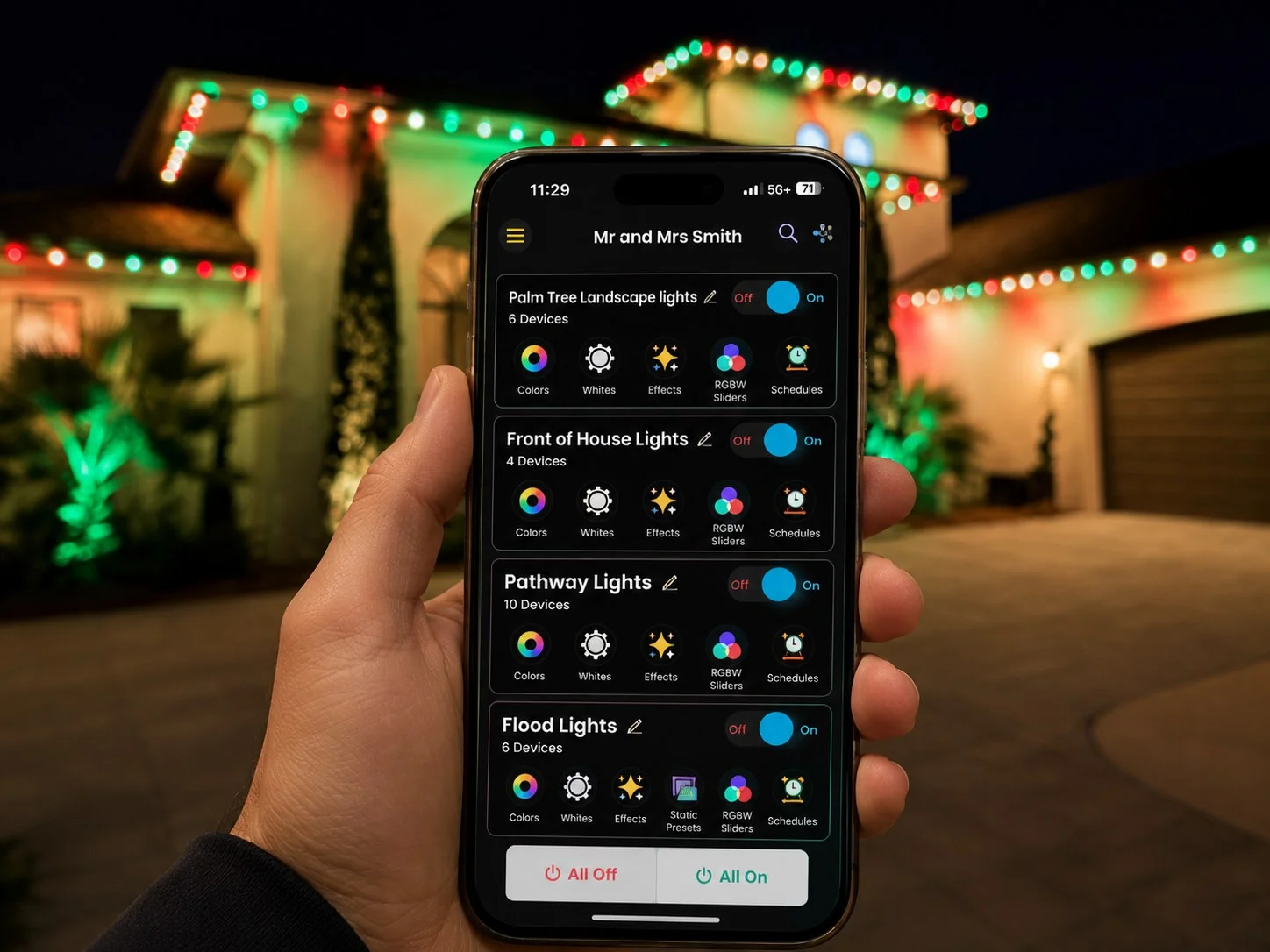 Controlling red and green holiday roofline lighting from the Brighter Nights Lighting Technologies app, phone in hand in front of the lit home