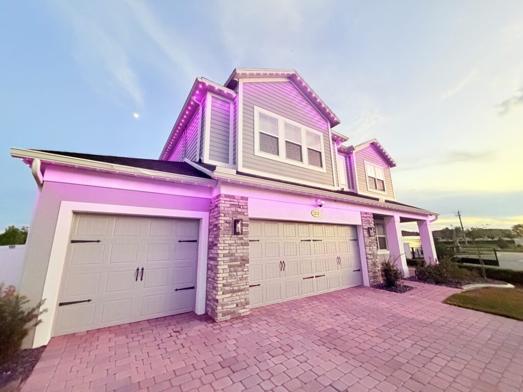 Two story home with roofline and soffit lighting glowing magenta pink at dusk in Sanford, Florida