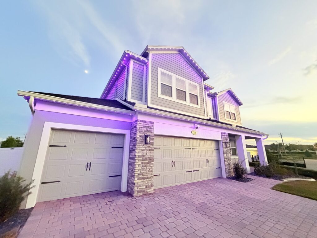 Two story home lit in violet with white roofline lights at dusk in Sanford, Florida