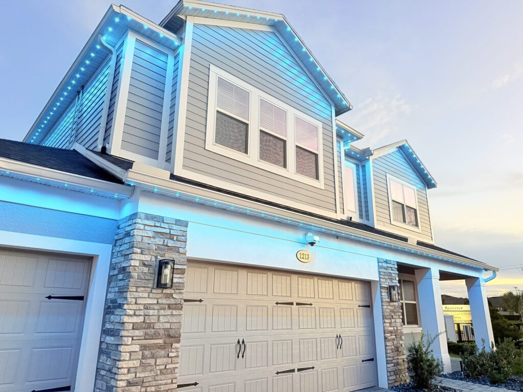 Close view of a two story home with bright aqua roofline lighting in Sanford, Florida