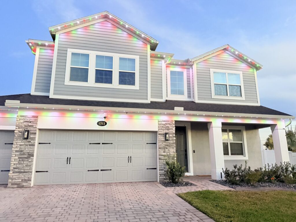 Two story home with red, green and white roofline lights and soft color wash in Sanford, Florida