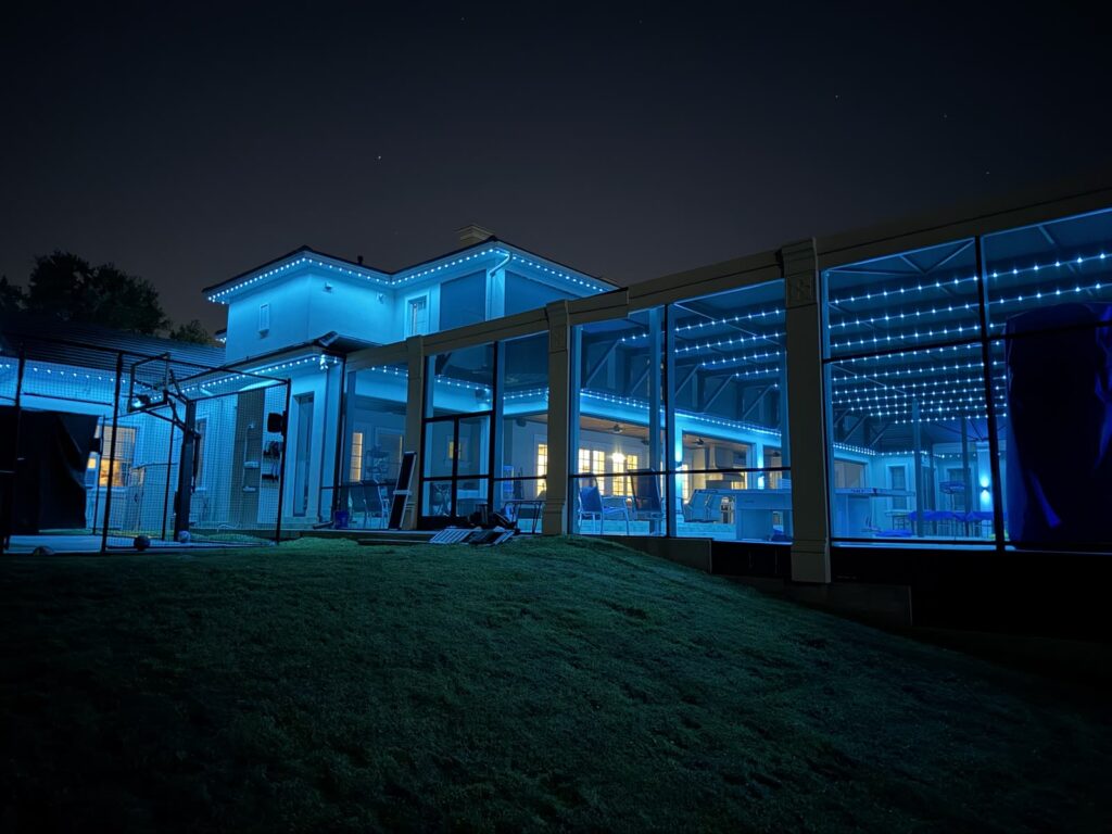 Close view of a blue lit pool enclosure showing track lighting rows and wall sconces beside the columns in Windermere, Florida
