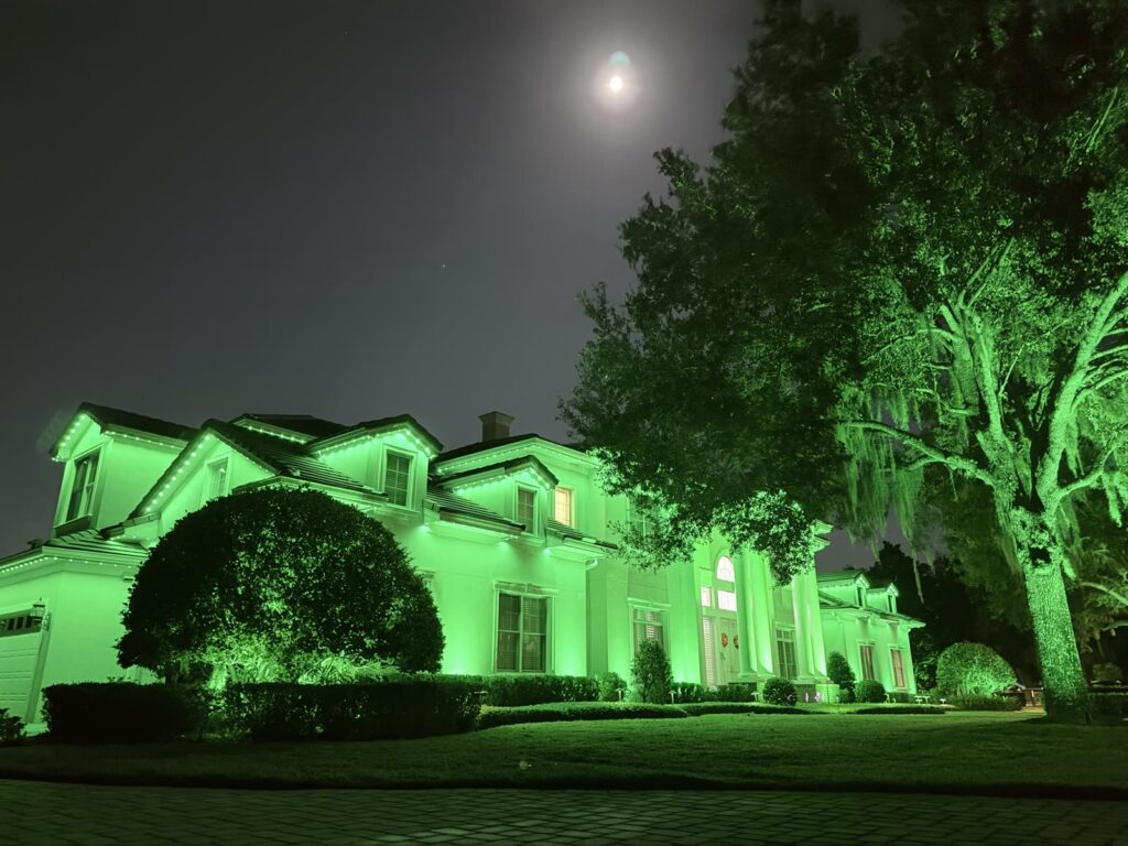 Home and landscape lit in bright green permanent outdoor lighting at night in Windermere, Florida