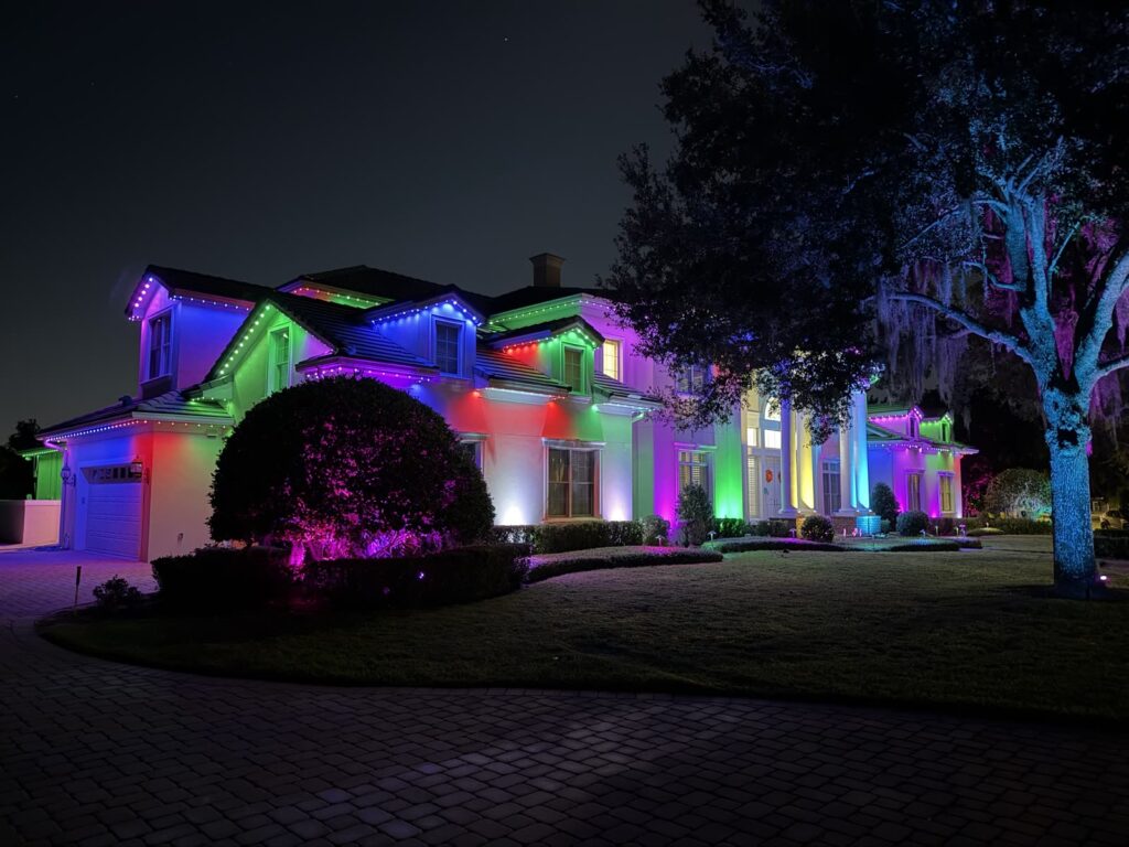Two story home with full color roofline lighting in purple, green, red and blue, installed by a certified installer in Windermere, Florida