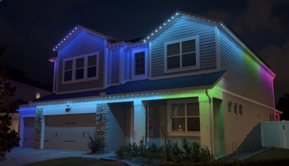 Two story home at night with a multicolor gradient flowing along the roofline
