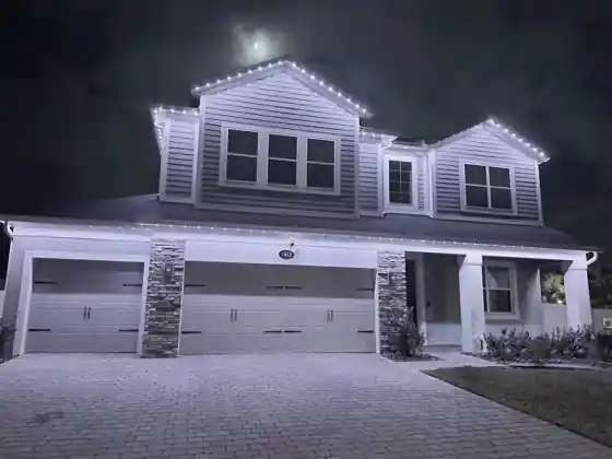 Home at dusk with cool white permanent roofline lights along the roof edge