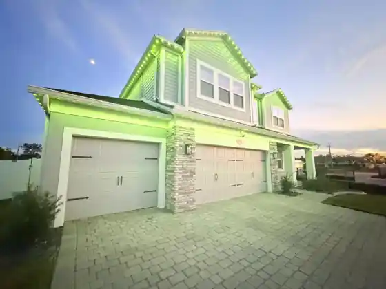 Home at dusk with green permanent roofline lights along the roof edge