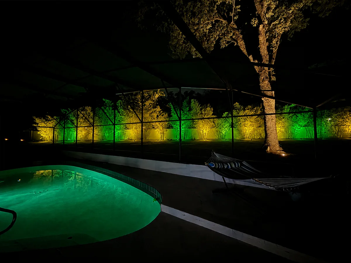 The same screened pool yard lit in green and gold for St Patrick&rsquo;s Day