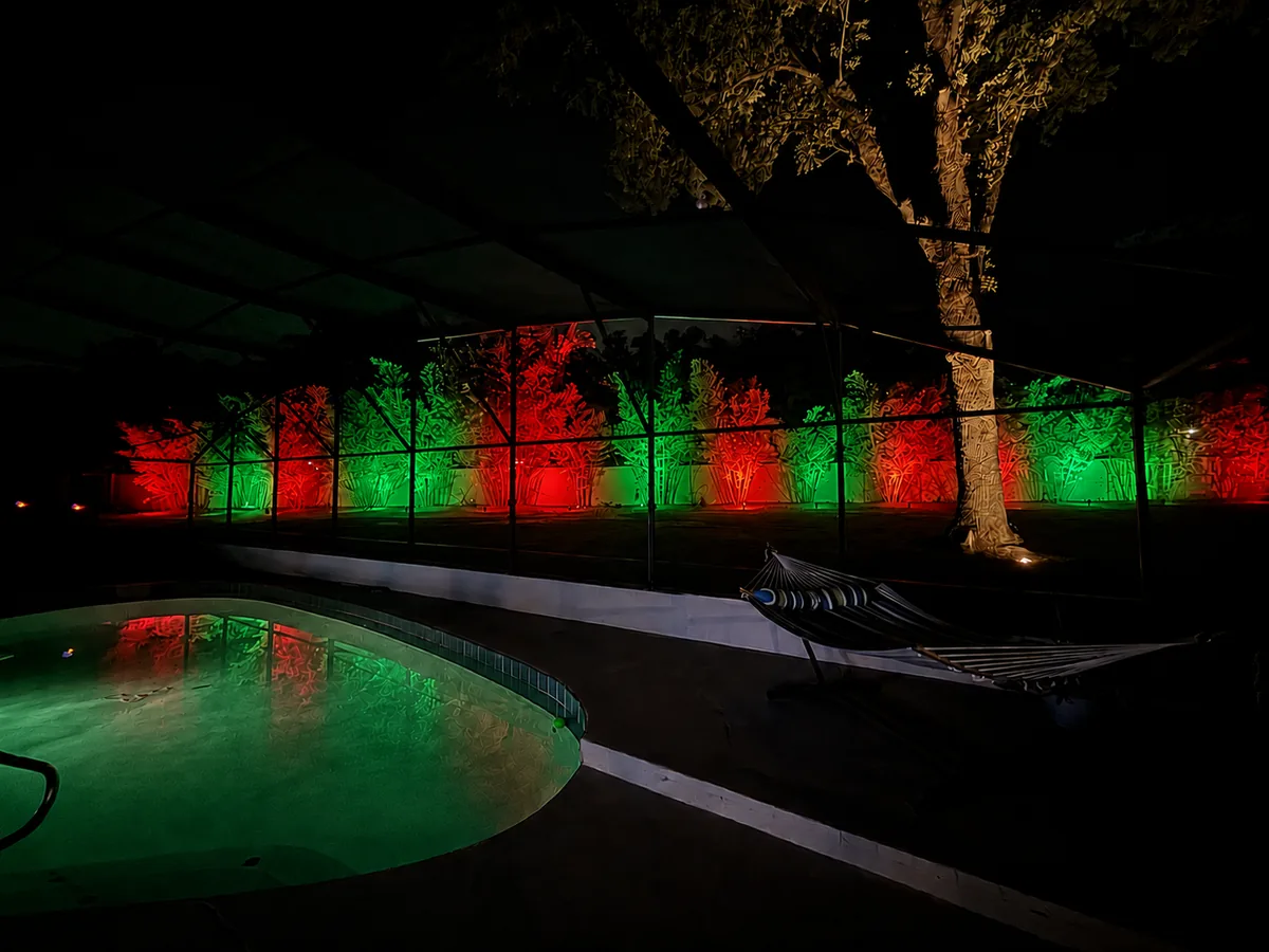 The same screened pool yard lit in red and green for Christmas