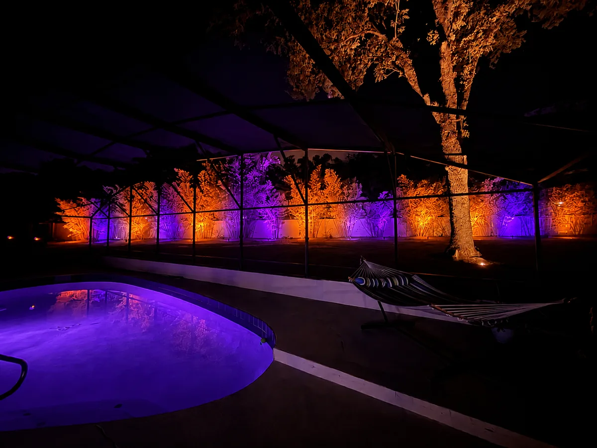 The same screened pool yard lit in violet and orange for Halloween