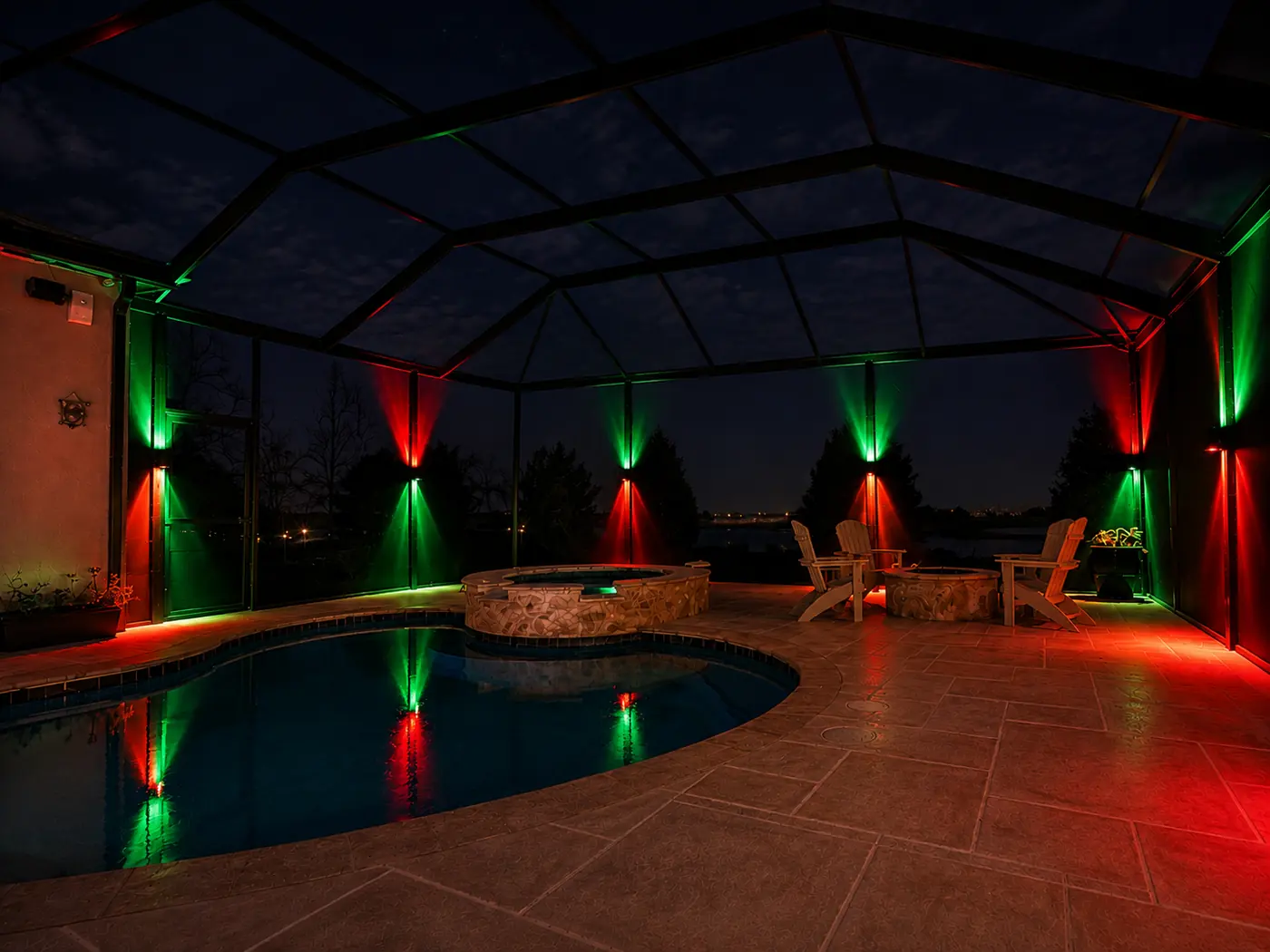 Sconce lighting on pool enclosure posts alternating red and green for Christmas, dual up and down beams reflected in the pool