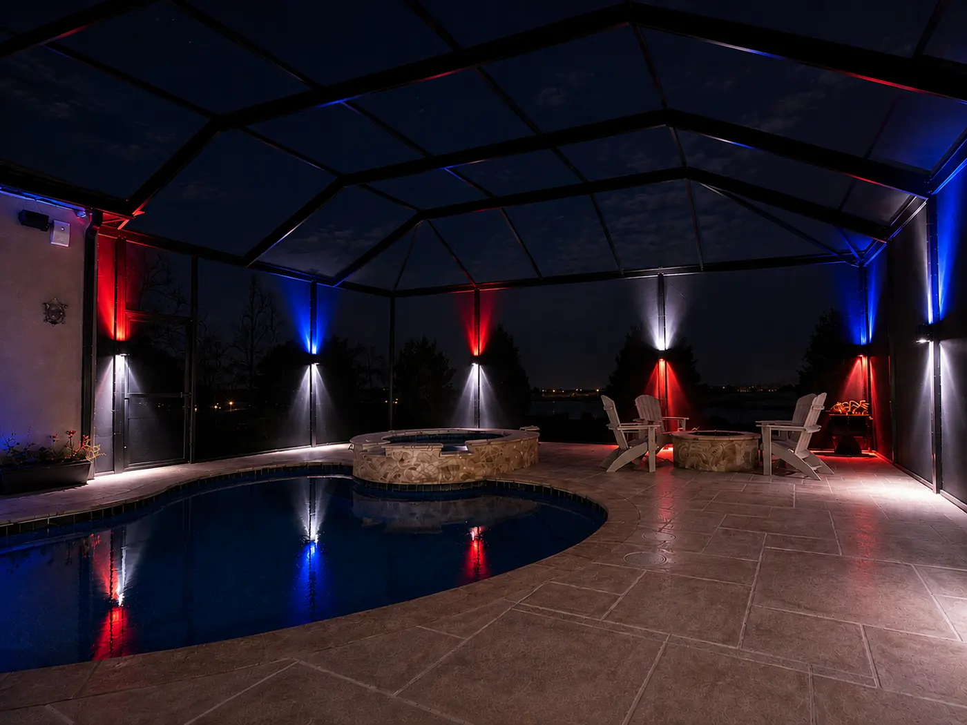 Sconce lighting on pool enclosure posts in red, white and blue for the 4th of July, reflected in the pool