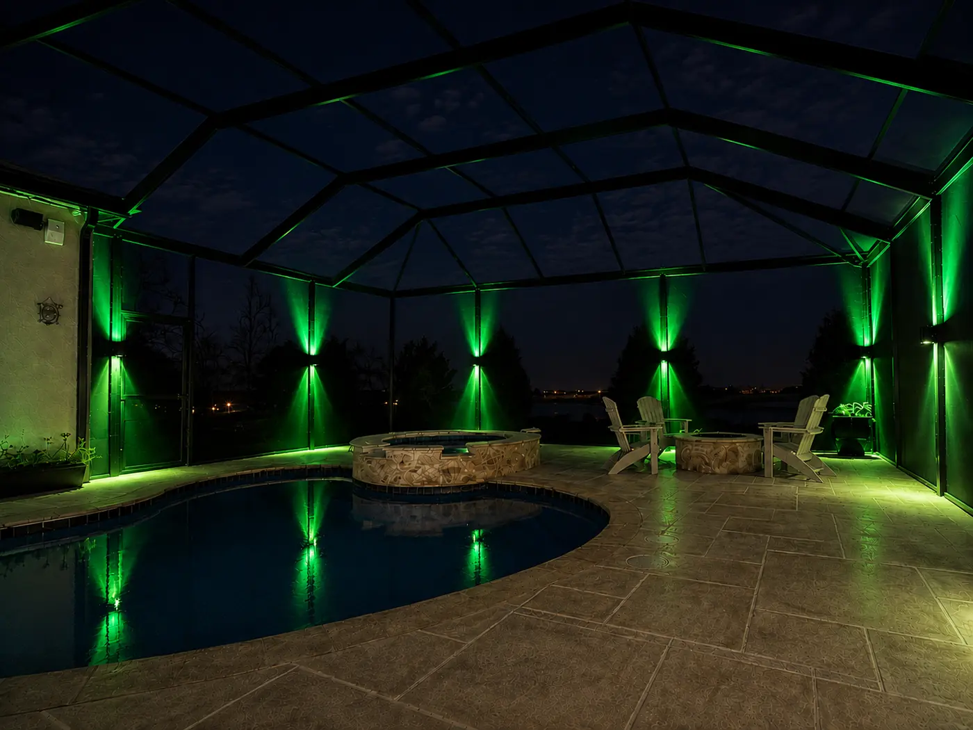 Sconce lighting on pool enclosure posts washed in solid green for St. Patrick's Day, dual up and down beams reflected in the pool