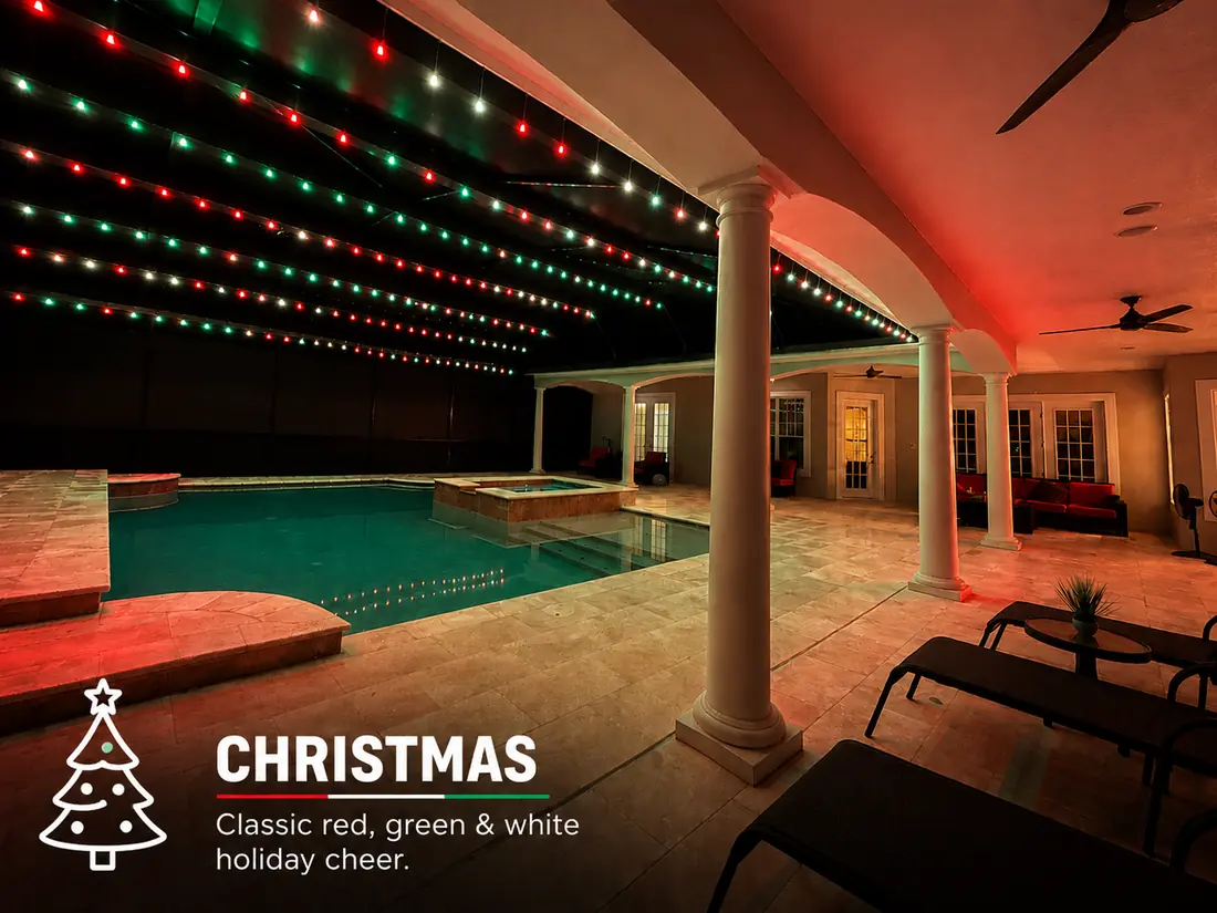 Christmas pool enclosure lighting: red, green and white BNLT track lights over a lanai pool at night