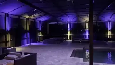 BNLT track lighting running live along every beam of a screened pool enclosure at night