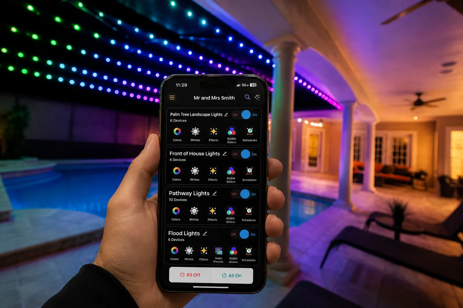 A homeowner holding an iPhone running the Brighter Nights Lighting Technologies app, with Palm Tree Landscape Lights, Front of House Lights, Pathway Lights and Flood Lights each listed as its own group, while the pool enclosure behind glows in green, blue and magenta