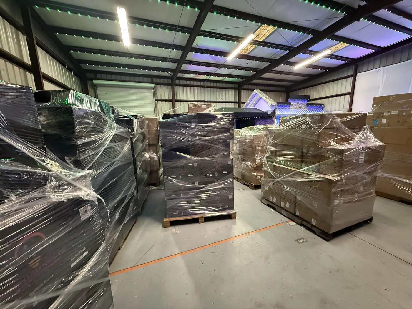 Wrapped pallets of product in a warehouse under installed lighting